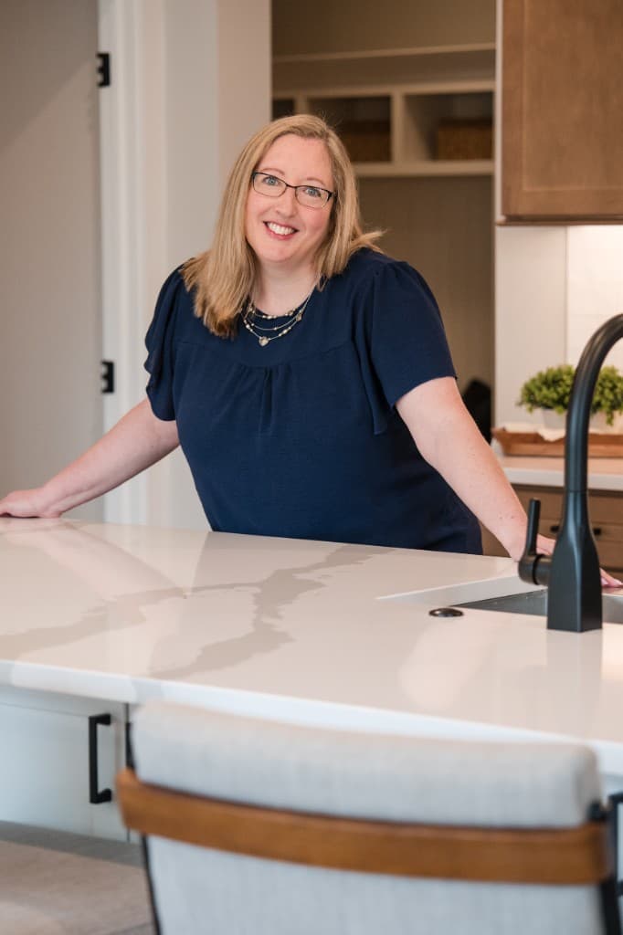 Melissa Beebe smiling beside a marble kitchen island